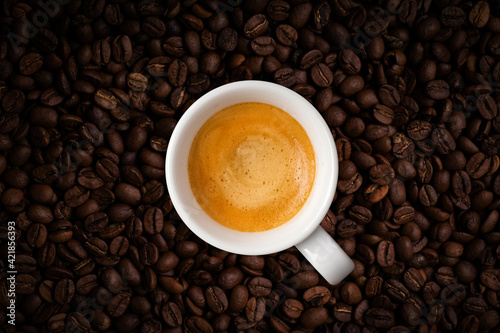 Cup of fragrant coffee on coffee beans background. View top