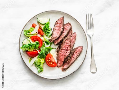 Delicious lunch - lettuce  cucumber  tomato salad and beef steak on a light background  top view