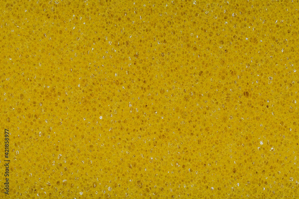 Yellow plastic scrubber with holes as a background. Cleaning sponge texture with visible porous close-up Yellow plastic scrubber with holes as a background. Cleaning sponge texture with visible porous close-up