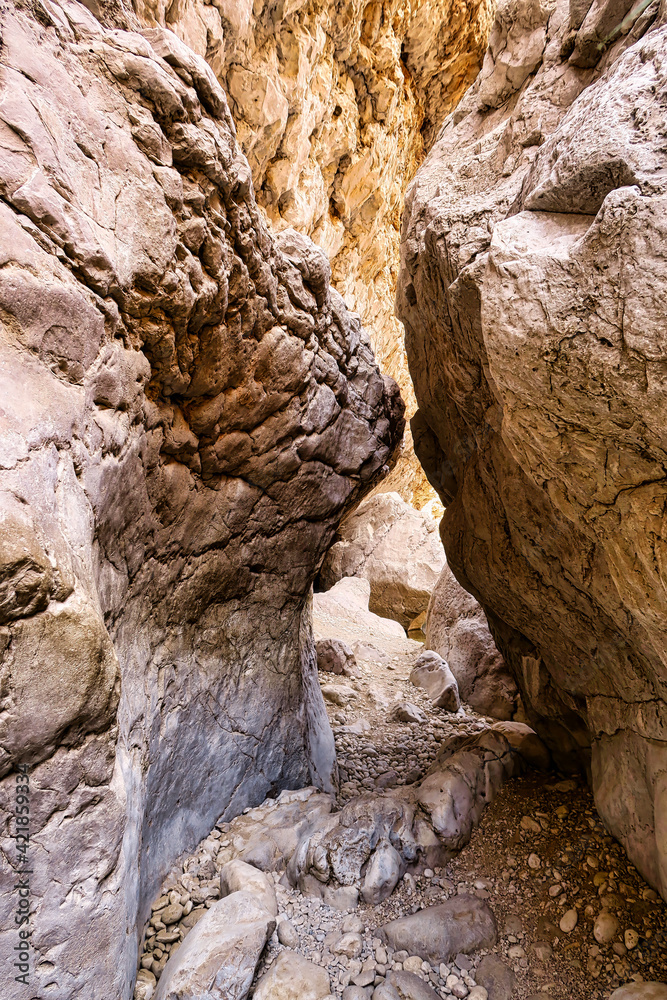 Huge sandstone rocks close to each other and a narrow passage in a canyon in Oman