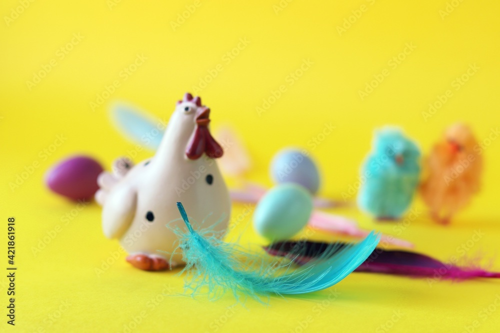Easter toy chicken, eggs and feathers on bright yellow background, congratulations concept, postcard