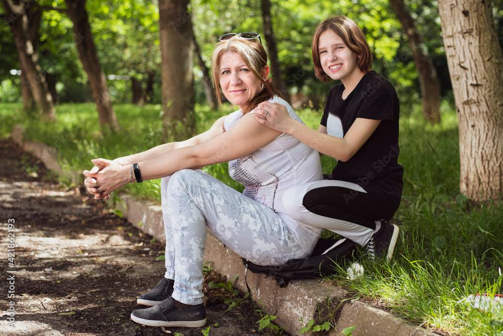 In the park, a woman and her teenage daughter communicate, spend time together, discuss teenage problems, learning difficulties, relationships with boys In the park, a woman and her teenage daughter communicate, spend time together, discuss teenage problems, learning difficulties, relationships with boys