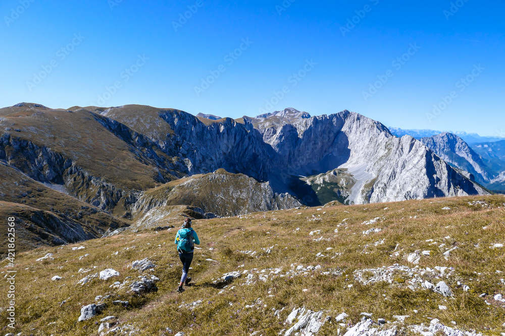 A woman with a hiking backpack hiking to the top of Hohe Weichsel in Austria. The woman in enjoying the calmness. The vast pasture is turning golden. Exploration and discovery. Endless mountain chains
