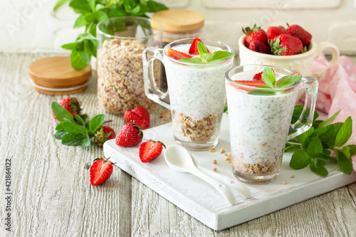 Healthy eating concept breakfast. Homemade granola with strawberry, yogurt, chia seeds, homemade granola and fresh berries on a wooden table. Copy space.