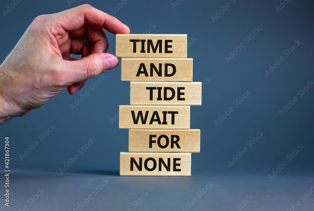 Time to action symbol. Wooden blocks with words time and tide wait for none. Beautiful grey background. Businessman hand. Business and time to action concept. Copy space. - obrazy, fototapety, plakaty 