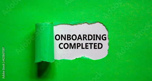 Onboarding completed symbol. Words 'Onboarding completed' appearing behind torn green paper. Beautiful green background. Business, onboarding completed concept, copy space.