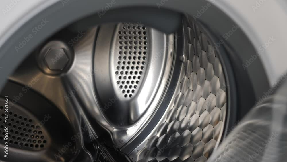 The camera slowly moves along the open washing machine and shows its