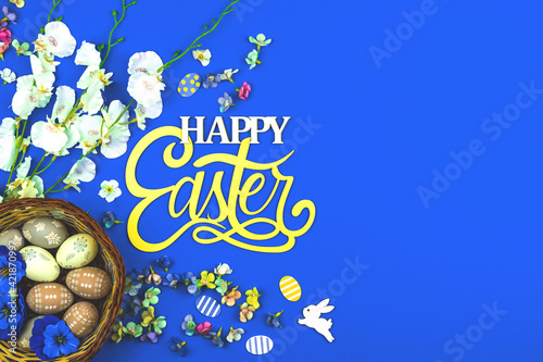 Happy Easter background with egg nests and spring flower, blue background and top view © FellowNeko