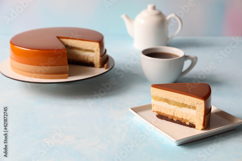 A piece of mousse cake with a cake a cup of tea and a teapot on the table