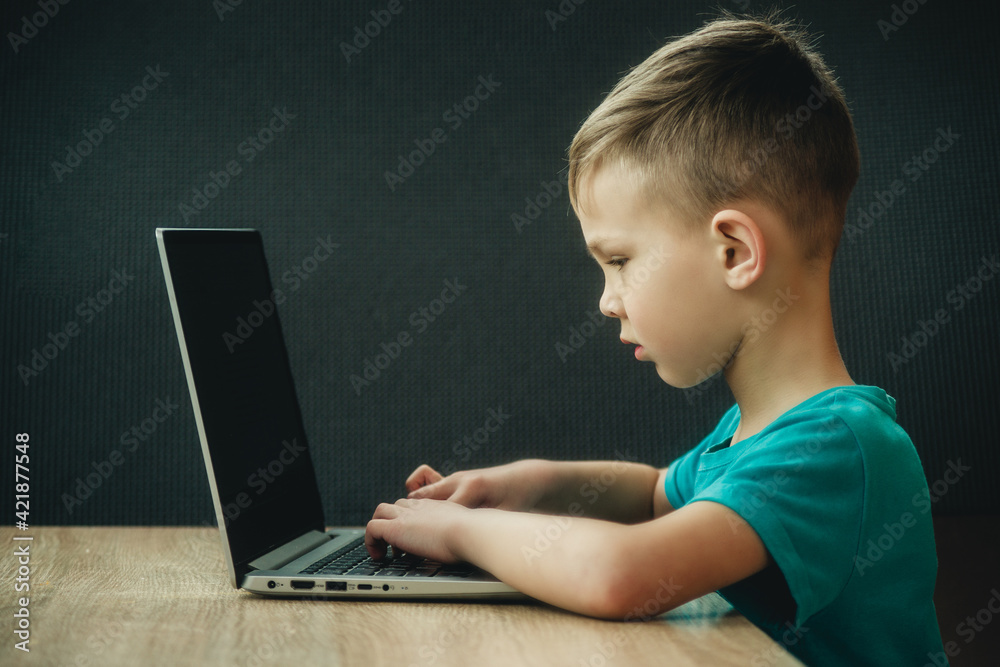 the boy is studying at the computer on a dark background the boy is studying at the computer on a dark background