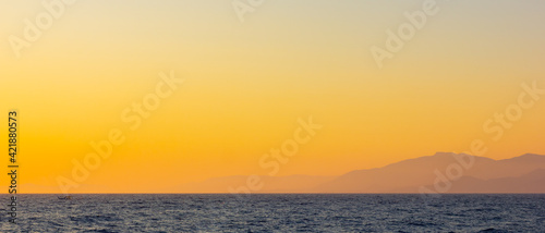 Seascape with fog and mountains. Seascape at sunset. View from the sea to the mountains in the haze. Dramatic scenes and the beauty of nature