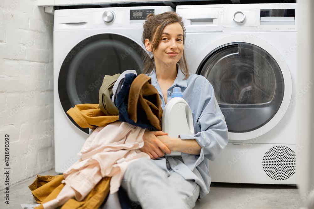 Woman with clean clothes and detergent in the laundry room at home Woman with clean clothes and detergent in the laundry room at home