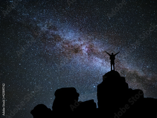 Man standing at mountain and looks in night sky photo