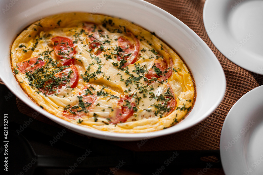 Omelet with tomatoes and cheese for breakfast in a white dish