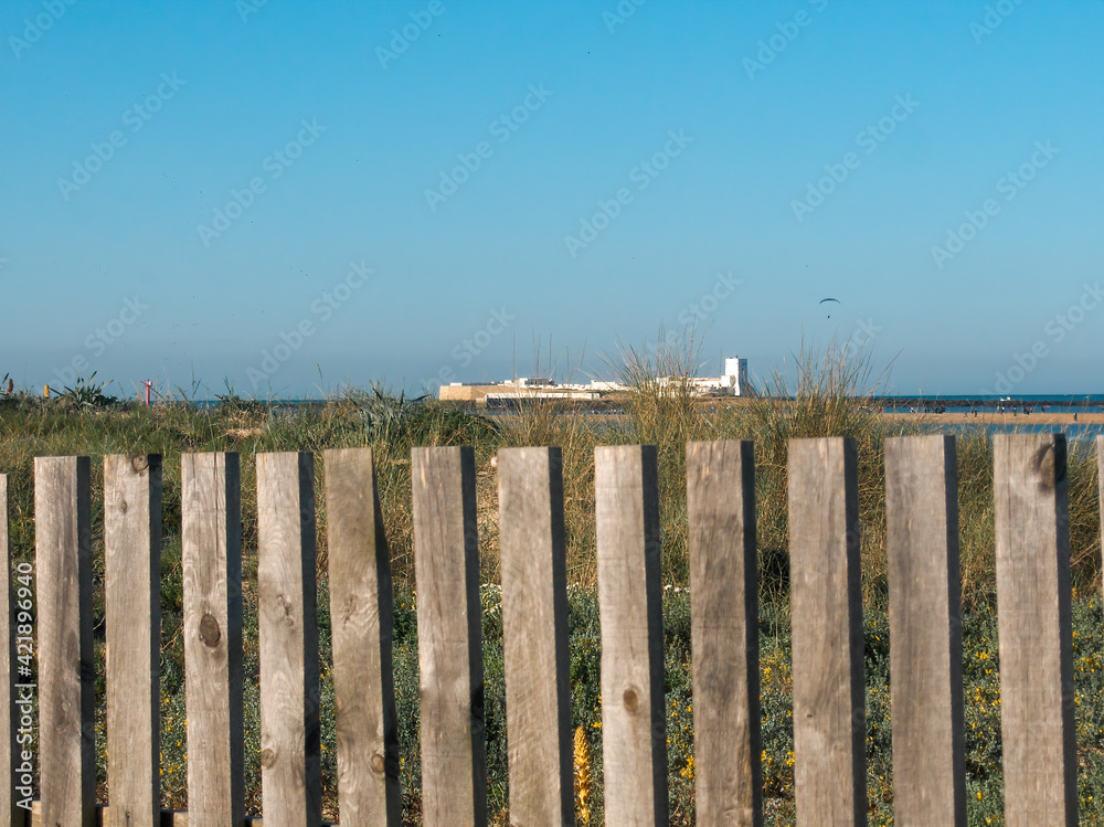 Distant view of the castle of Sancti Petri behind the wooden fences of the beach in Chiclana de la Frontera, on the coast of Cadiz, Andalusia, Spain