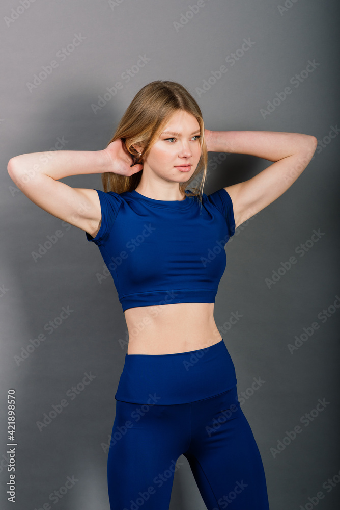 Portrait of young sporty woman smiling while sitting isolated on grey background Portrait of young sporty woman smiling while sitting isolated on grey background