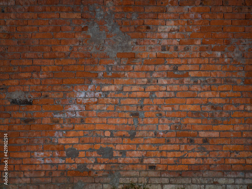 Combined texture of red, rotten, rusty, old brick wall with a white dirt base. The background is covered with mold, frost brickwork in an abandoned factory building. Dark lighting.