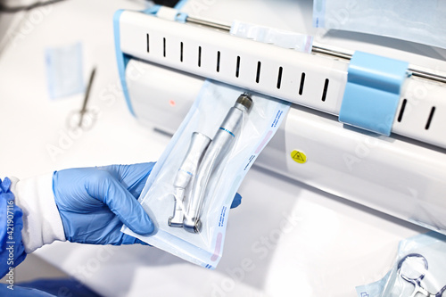 Sterilizing medical instruments in autoclave. Dental office. Close up dentist assistant's hands holding packaged with vacuum packing machine medical instruments ready for sterilizing in autoclave.