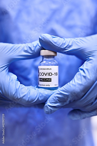 Female doctor in blue gloves holding COVID-19 vaccine. Healthcare and Medical concept. Selective focus