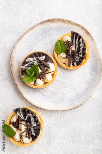 Sweet tartlets with chocolate and cheese cream on a gray concrete background, flat lay.
