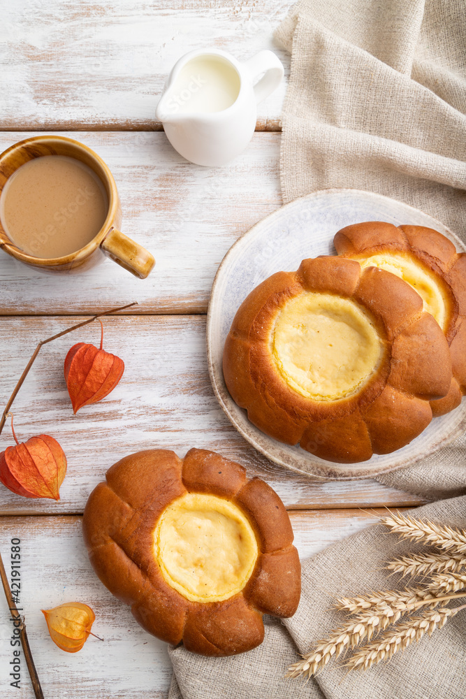 Sour cream bun with cup of coffee on a white wooden background. top view. Sour cream bun with cup of coffee on a white wooden background. top view.