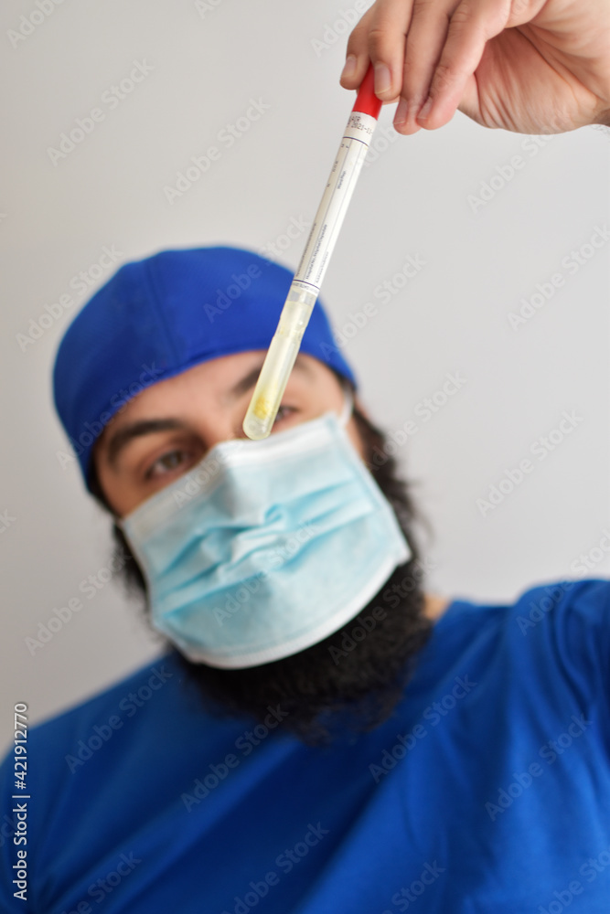 Nurse holding a tube. Rotavirus test. Man wearing a face mask grabbing a sample of feces to examined in a laboratory Nurse holding a tube. Rotavirus test. Man wearing a face mask grabbing a sample of feces to examined in a laboratory