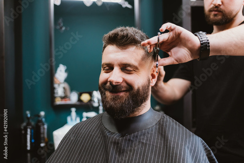 Happy contented male client of barbershop sitting in chair