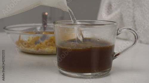 Young woman makes instant coffee with milk. Glass goblet close up. The girl prepares breakfast.