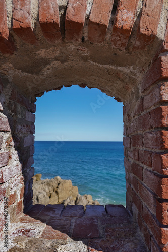 View of the Mediterranean Sea through a small window in the brick wall of the fortress. Antibes  France.