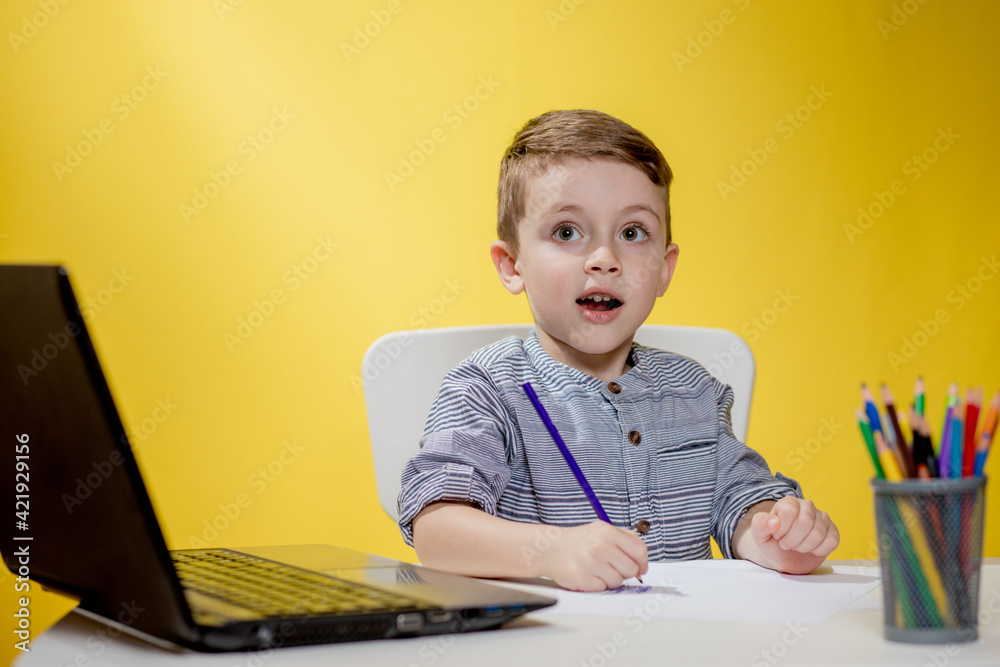 Happy Child using digital laptop doing homework on yellow background. Social Distancing, E-learning online education Happy Child using digital laptop doing homework on yellow background. Social Distancing, E-learning online education