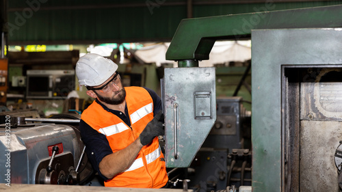 Mechanical engineer or worker in safety set working with heavy machine in a factory to check the production system.   