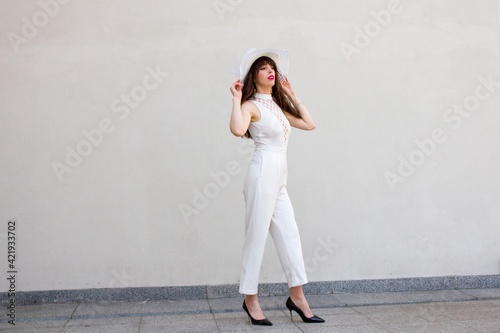 Φωτογραφία A young, beautiful and slender brunette, with long hair, wearing a white hat and