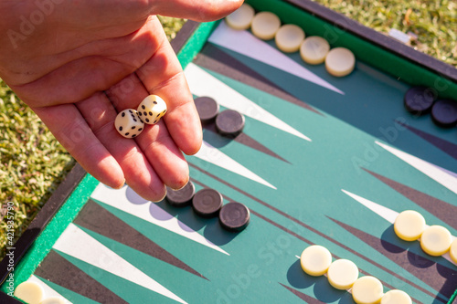 Obraz na plátne Hand Holding Dice Over A Green Backgammon Set