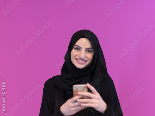 Young muslim businesswoman in traditional clothes or abaya using smartphone