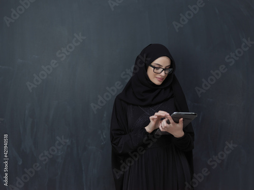 Young Arab businesswoman in traditional clothes or abaya with tablet computer