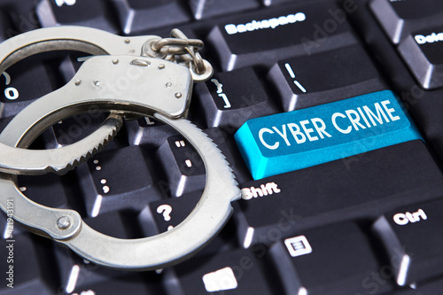 Handcuff with cybercrime text on keyboard