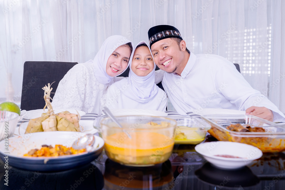 Muslim family smiling at the camera during dinner Muslim family smiling at the camera during dinner
