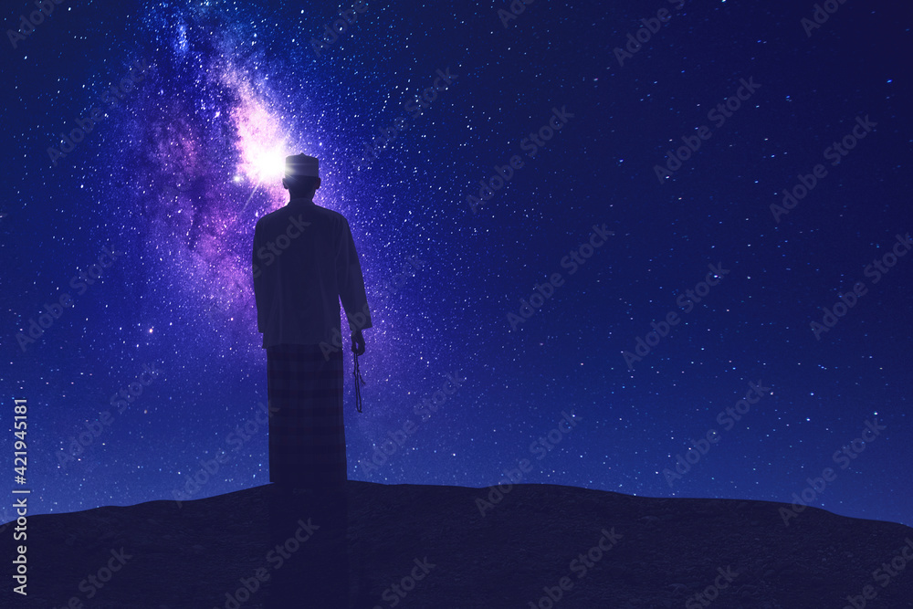 Muslim man holding prayer beads on hill at night