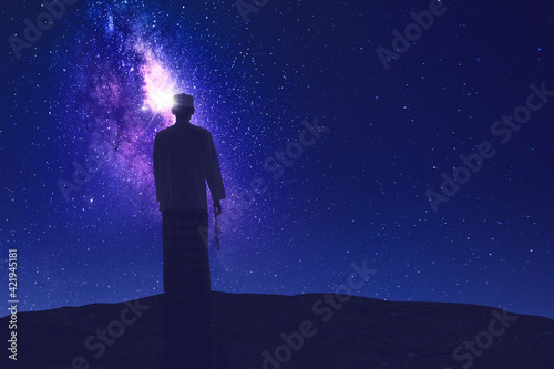 Muslim man holding prayer beads on hill at night