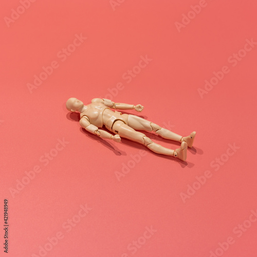 Slika na platnu Miniature doll of a man lies on a coral background