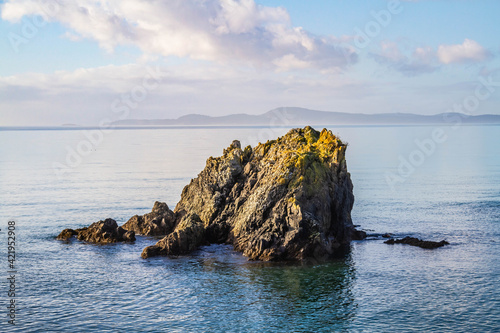 A single rock protruding from the surrounding blue ocean waters.