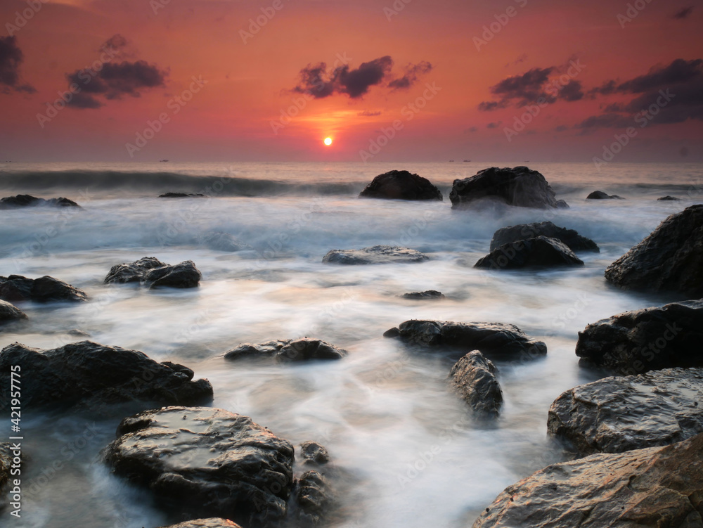 Beautiful natural seascape wave moving on the rock during sunrise