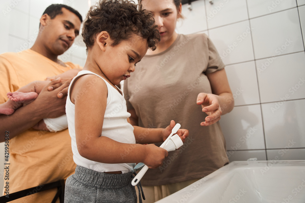 Mother, father and two child boy are brushing their teeth in the bathroom