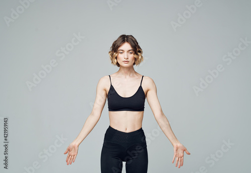 woman in black jeans on gray background doing exercises cropped view © SHOTPRIME STUDIO