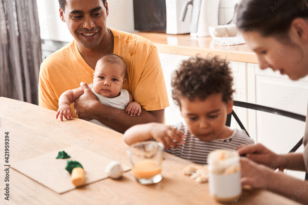 Family of four preparing to the breakfast at the kitchen at the table Family of four preparing to the breakfast at the kitchen at the table