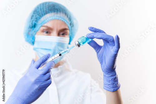 Doctor in gloves filling up syringe from bottle with vaccine  medicine