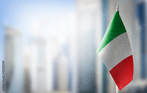 A small flag of Italy on the background of a blurred background