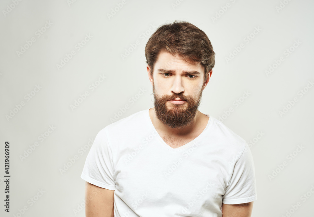 Guy in a white T-shirt on a light background emotions sad face cropped view