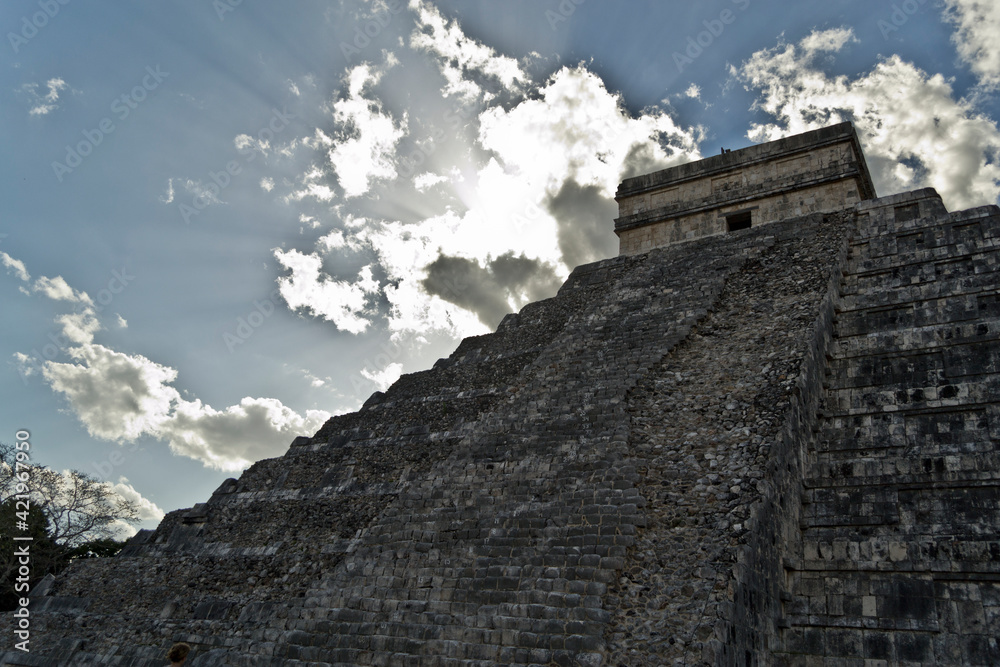 Chichén Itzá con nubes de fondo y resplandor solar Chichén Itzá con nubes de fondo y resplandor solar