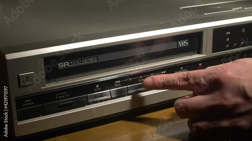 Inserting a VHS tape into a VCR and pushing the PLAY button